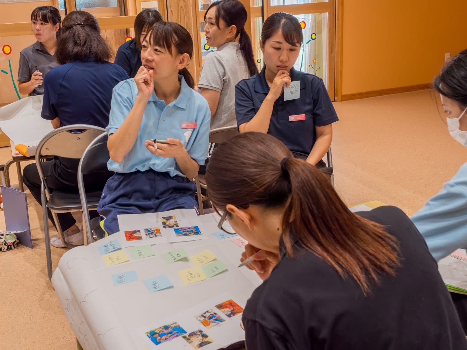 写真と付箋を並べた模造紙を囲み、グループワークで話し合う先生たち