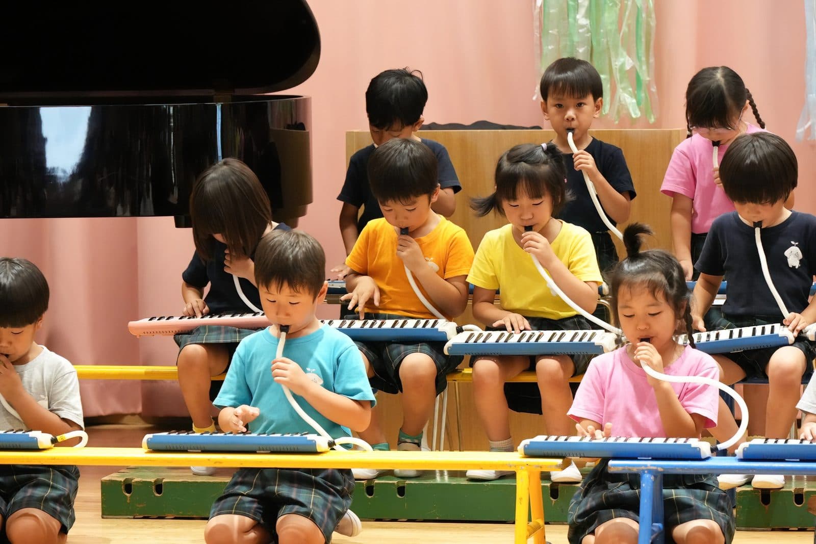 ホールのステージで、メロディオンを合奏する子どもたち