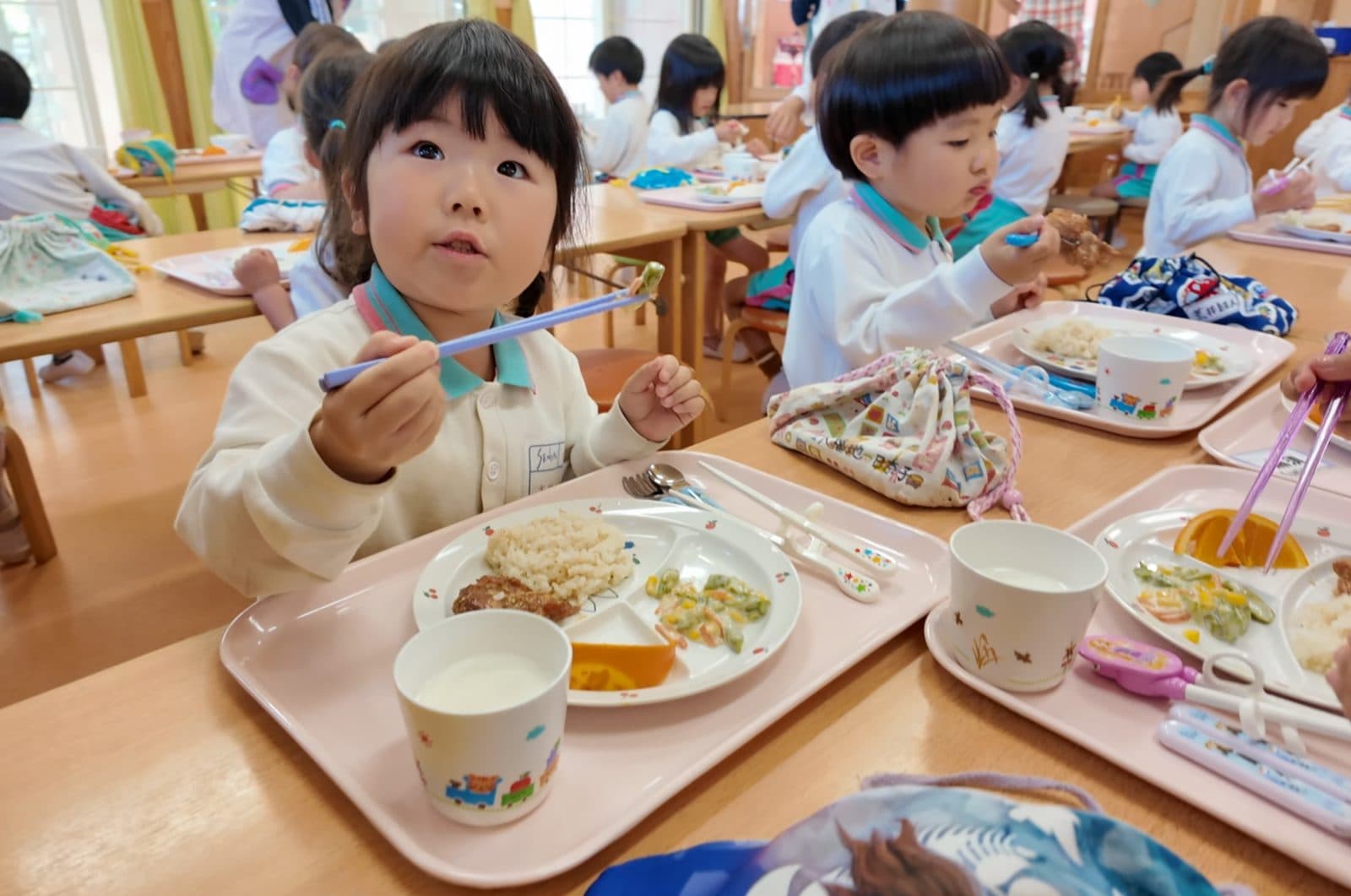 お箸をつかって自園給食を食べる子どもたち
