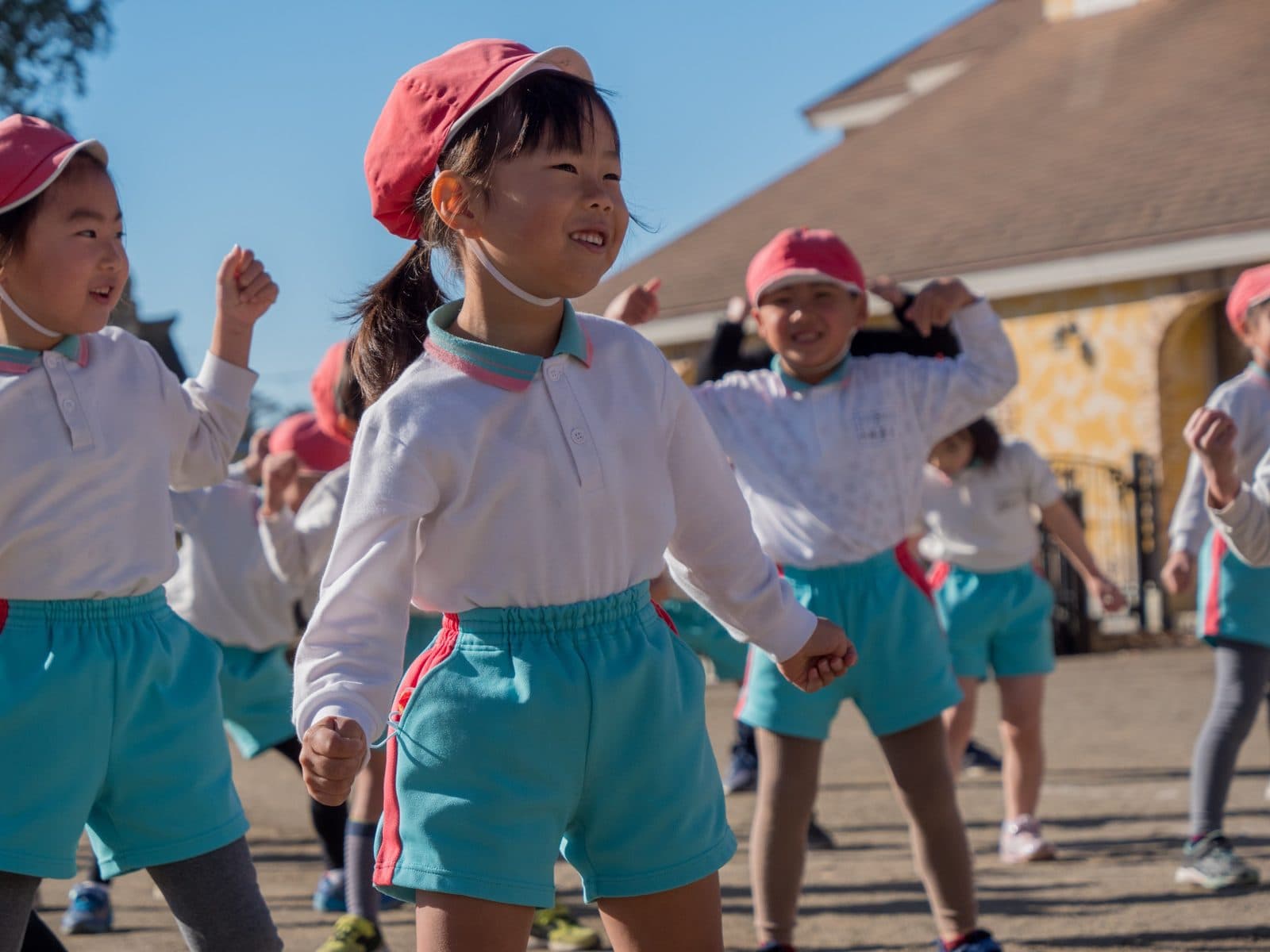 青空の下、笑顔で準備体操をする子どもたち