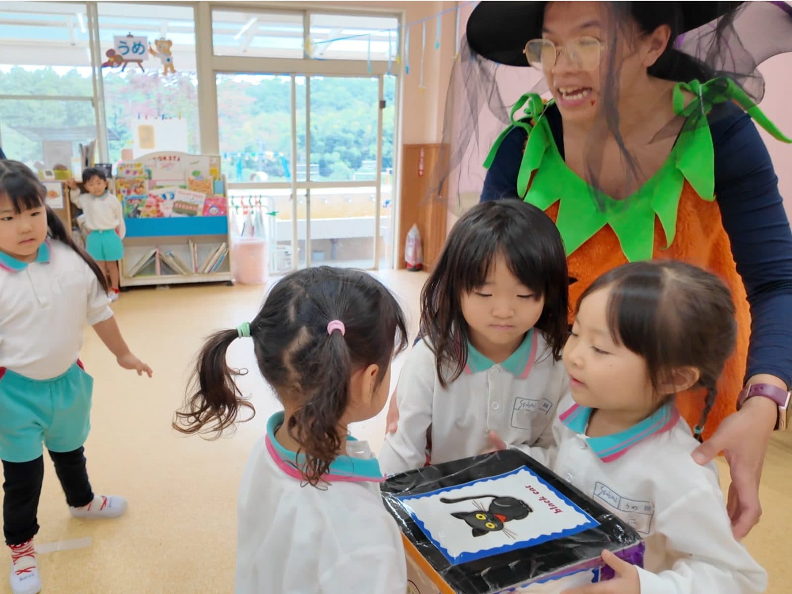 仮装した講師と英語のカードあそびを楽しむ子どもたち