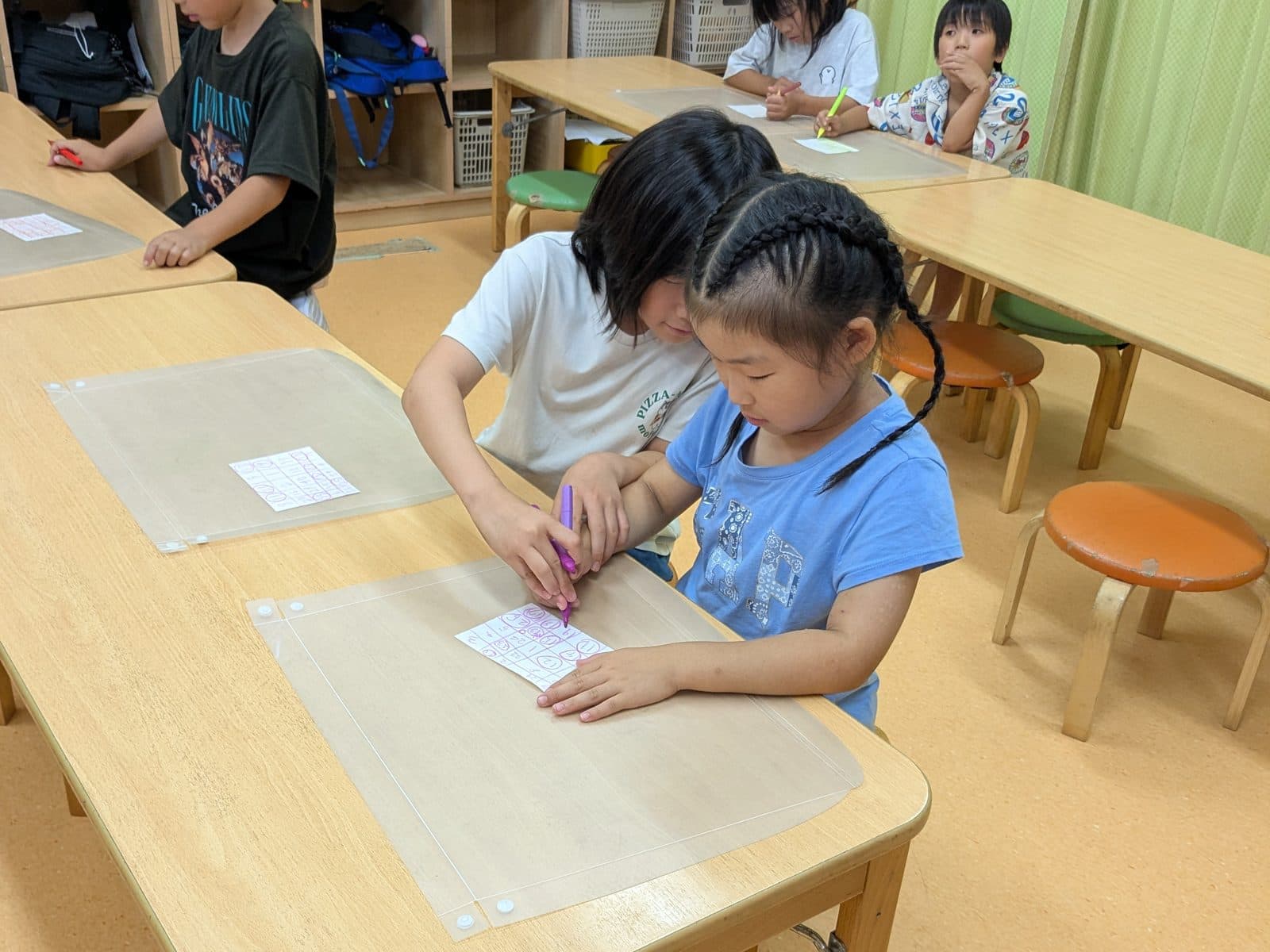 机で年上の子が年下の子に教えている様子(教え合いながら)