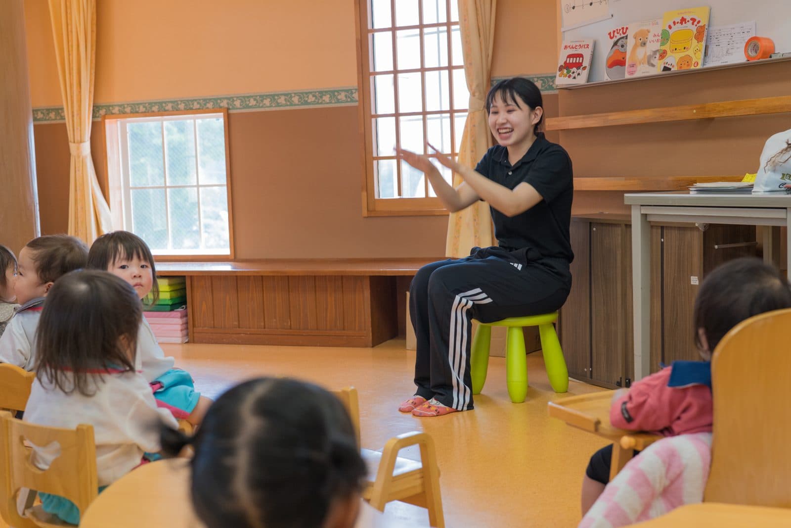 0〜2歳児の前で手あそびをしながら大きく笑う先生